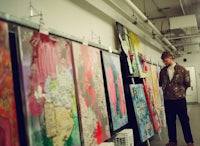 a man standing in front of a room full of paintings